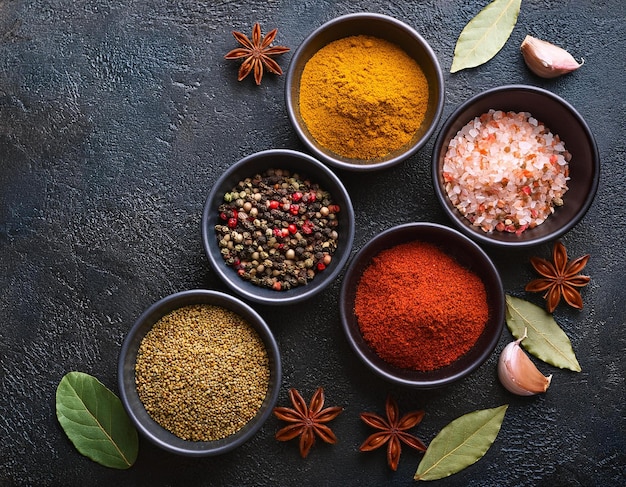 Set of various spices and herbs on black slate background Pepper