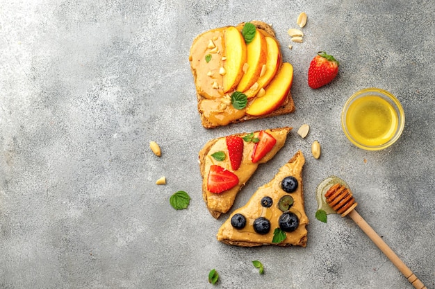 Set of various toast with whole grain bread, peanut butter, honey, mint, peanut, nectarine, blueberry and strawberry. healthy breakfast concept