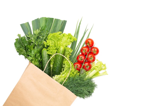 A set of vegetables and herbs in a paper bag isolated on white background. Concept: Shopping in a supermarket or market and Healthy Vegetarian Food.