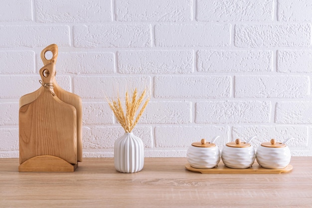 A set of white ceramic storage jars and wooden cutting boards in the interior of an ecofriendly kitchen minimalism Eco items