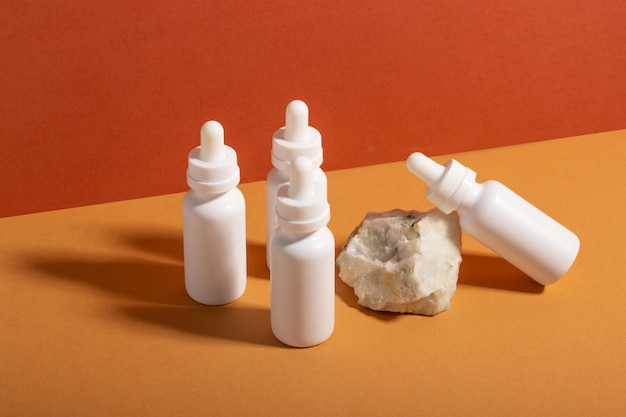 Set of white cosmetic bottles with a dropper on a beige background with hard shadows The concept of face and body care at home and in a beauty salon