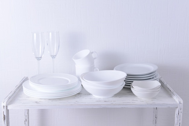 Set of white dishes on table on light background