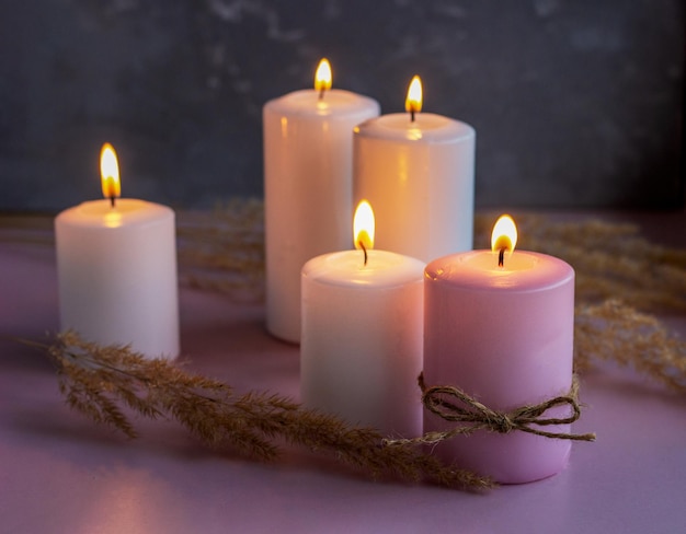 Set of white and pink wax candles with dried flowers in low lights