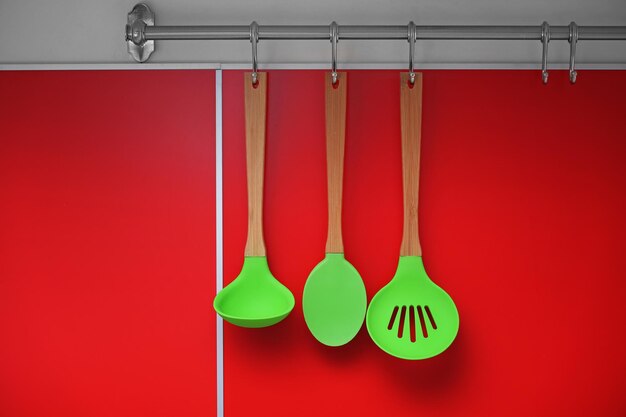 Photo set of wooden kitchen utensils hanging on wall