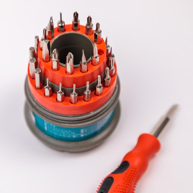 A set of working tools with a screwdriver and bits for repair in an open plastic box with iron bits