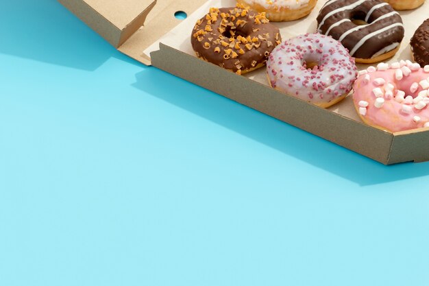 Set of yummy colorful donuts in paper box on blue online delivery take away food