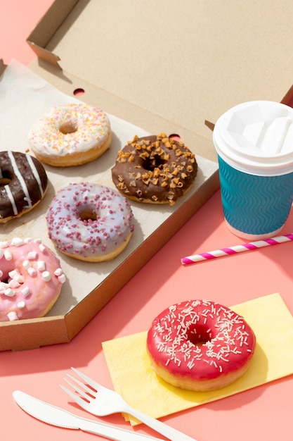 Set of yummy colorful donuts in paper box on pink surface