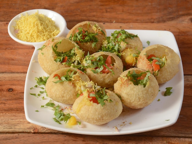 Sev puri is a famous midday snack in india served over a rustic wooden background selective focus