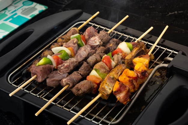 Seven skewers on an electric grill made of pork chicken onion pepper bovine