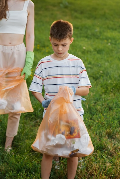 A sevenyearold boy at sunset is engaged in garbage collection in the park Environmental care recycling