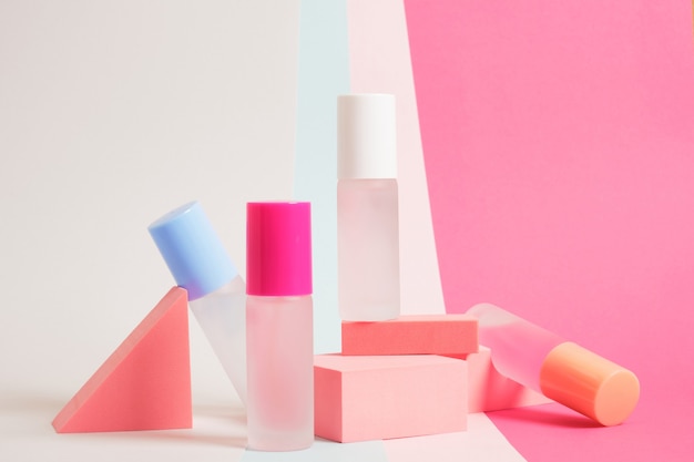 Several bottles of perfume of different colors on a bright colorful background, mock up perfume bottles on pink geometric stands