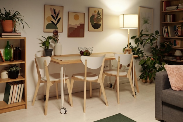 Several chairs standing around dinner table by wall with group of paintings