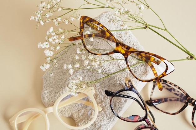 Several different trebdy eye glasses with fashion frames and concrete podium on beige background