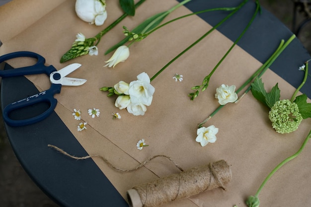 Several different types of white flowers laid out on parchment paper on a table in the garden