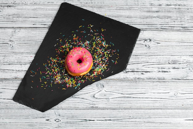 Several fresh donuts in a black ceramic plate on a wooden table