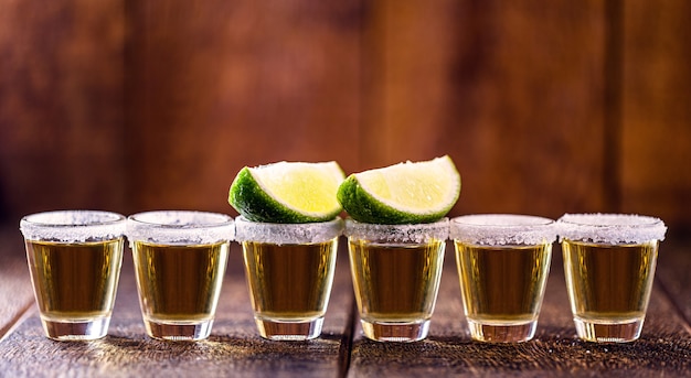 Several glasses of tequila lined up, a drink of Mexican culture, made of distilled alcohol, lemon, salt and blue agave