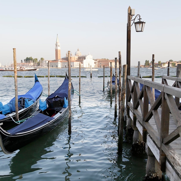 Several gondolas and the background the church and monastery of San Giorgio Maggiore Venice Italy