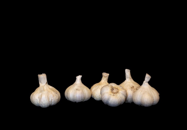 Several heads of garlic on a black background