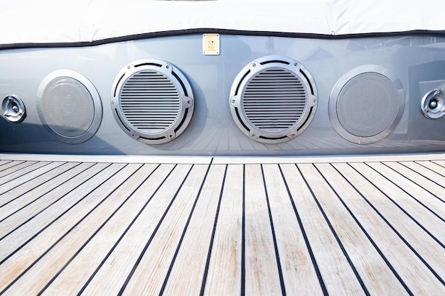 Several music speakers are built into the body of a sofa on the teak deck of a luxury yacht