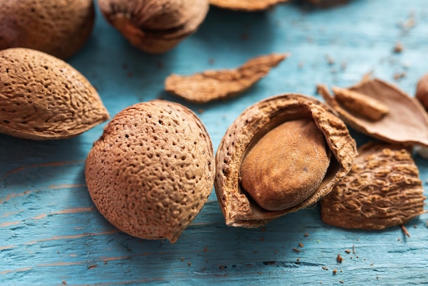 Several opened organic almonds on a blue wooden background nuts healthy snack Prunus dulcis