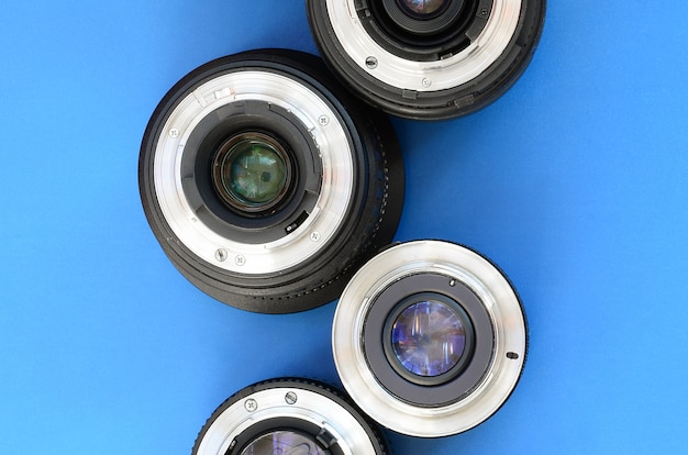 Several photographic lenses lie on a bright blue background. Space for text 