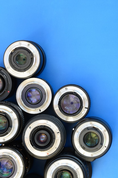 Several photographic lenses lie on a bright blue background. Space for text