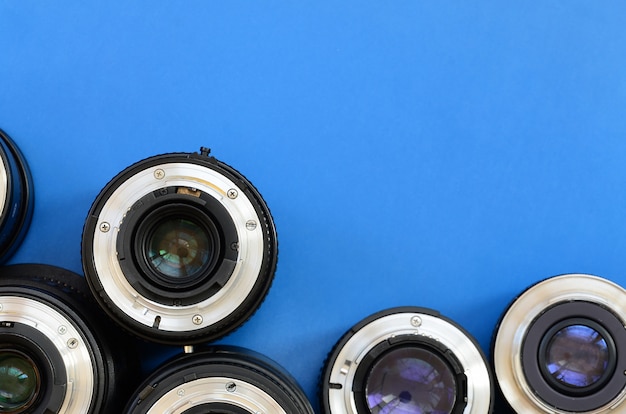 Several photographic lenses lie on a bright blue background. Space for text