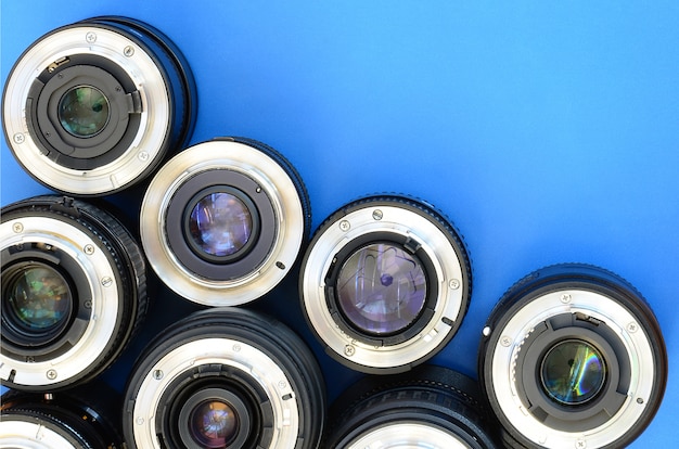 Several photographic lenses lie on a bright blue background. Space for text