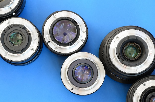 Several photographic lenses lie on a bright blue background. Space for text