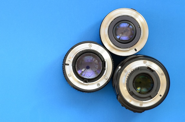 Several photographic lenses lie on a bright blue background. Space for text