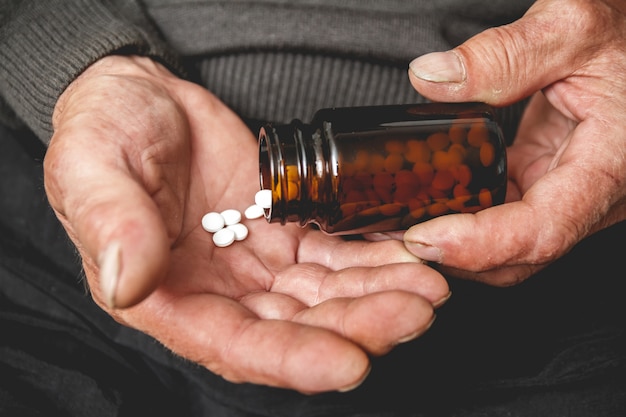 Several pills in the hands of an elderly person