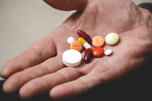 Several pills in the hands of an elderly person