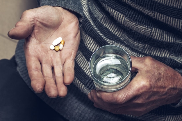 Several pills in the hands of an elderly person