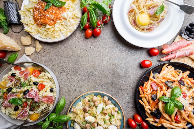 Several plates of pasta with different kinds of sauce over stone. Concepts of Italian food.