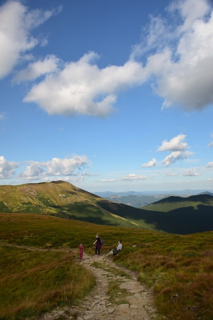 Several travelers walking along the ridge to the top of the mountain against the blue sky