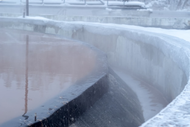 Sewage treatment plant in winter, icy primary settling tanks