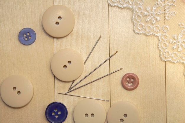 Sewing accessories. Buttons, needles, lace on a wooden table. The concept of hobby, sewing and needl