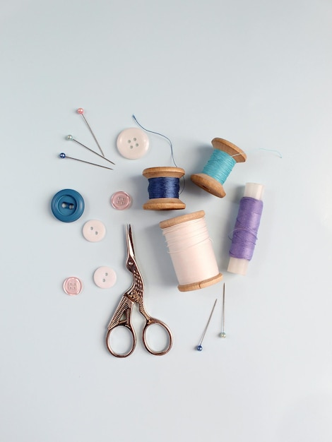 Sewing accessories and fabric on a blue background Sewing threads needles pins fabric buttons and sewing centimeter top view flatlay