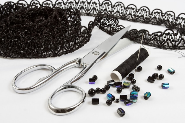 Sewing background: metal scissors,black threads, lace and beads