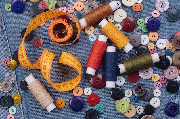 Sewing buttons, yellow measuring tape and thread spools.