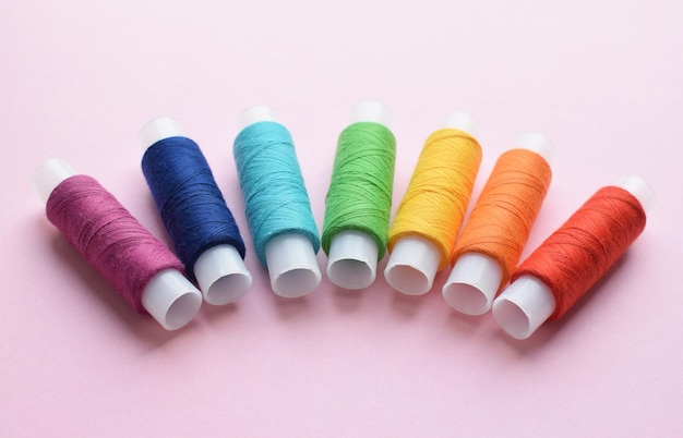 Sewing colored threads on a pink background Cotton threads in spools