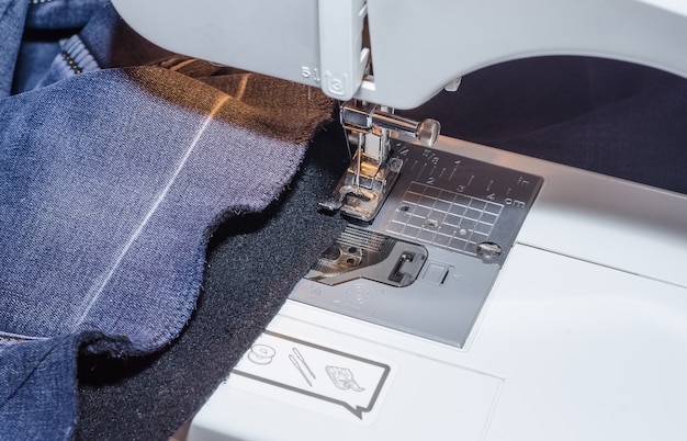 Photo sewing machine foot on denim fabric overcasting process