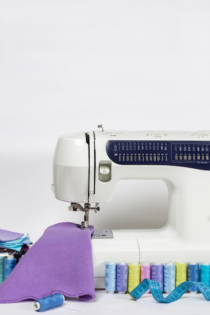 Sewing machine and threads on white desk with white background and copy space