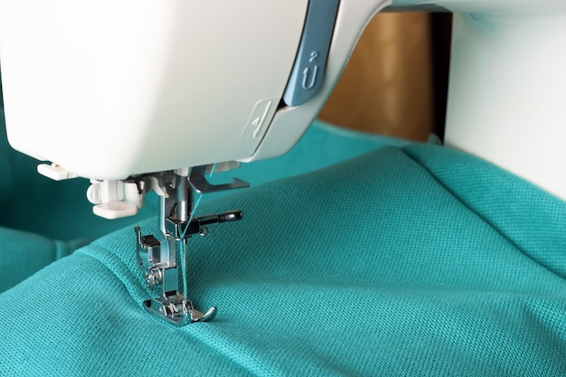 Sewing machine with turquoise fabric and thread, closeup