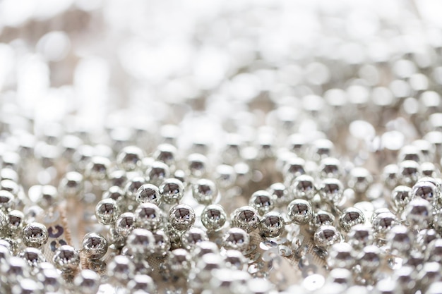 sewing, texture, background, christmas and holiday decoration concept - close up of silver beads on sparkling sequined textile texture