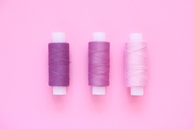 Sewing thread kit of lilac pink violet crimson sewing thread on a pink paper background