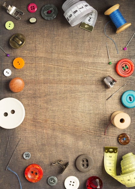 Sewing tools and accessories on wooden table background, top view