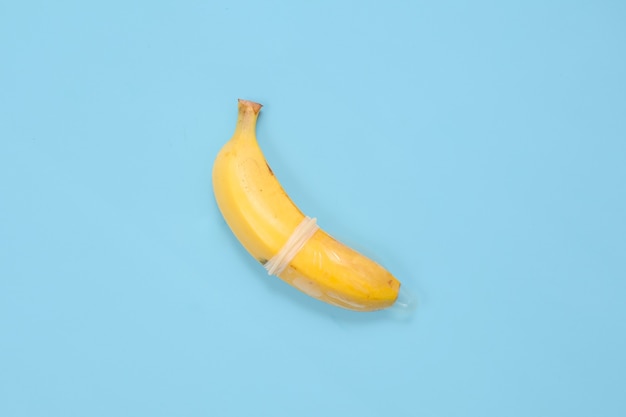 Sex education with banana and condom isolated on blue background