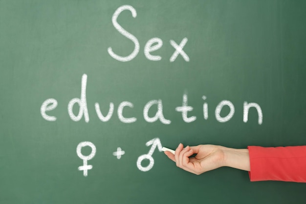 Photo sex education woman drawing male gender sign on green chalkboard closeup