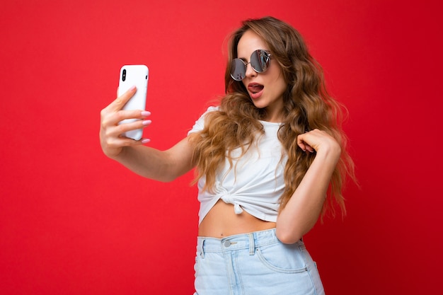 Sexy amazing beautiful young woman holding mobile phone taking selfie photo using smartphone camera